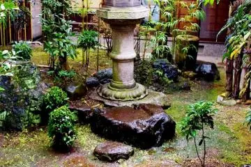 A lone stone lantern standing amidst a damp, mossy garden (Photo: Janet Heineck)