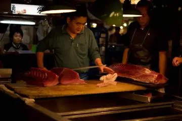 While fresh tuna is cut up with huge knives