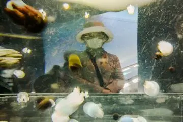 A woman wearing a mask on the other side of a jellyfish tank in Osaka Aquarium Kaiyukan. (Photo: <a href="https://www.flickr.com/photos/lain32/8023037132/" target="_blank" rel="noreferrer noopener nofollow">Lain</a>)