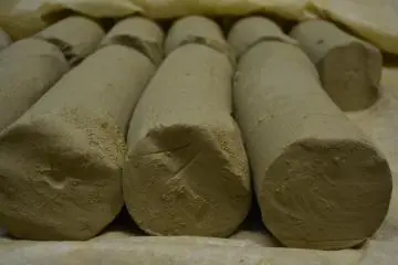 The clay sheets are placed in a mixer to produce cylindrical blocks. After further kneeding by hand to remove inconsistencies in the softness and hardness of the clay, it can be used in pottery making.