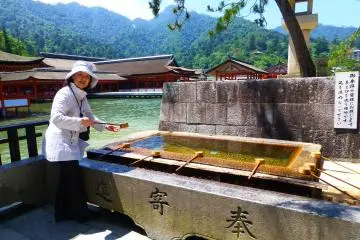 Kotoe demonstrating how to cleanse your hands before entering the Itsukushima shrine