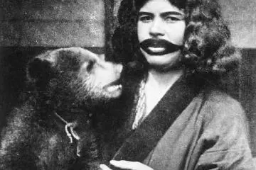 Ainu woman with tattoo (Photo: <a href="https://upload.wikimedia.org/wikipedia/commons/thumb/c/cc/Ainu_woman_with_mouth_tattoos_and_live_bear.jpg/460px-Ainu_woman_with_mouth_tattoos_and_live_bear.jpg" target="_blank" rel="noreferrer noopener nofollow">Juliet Bredon</a> / Public Domain)
