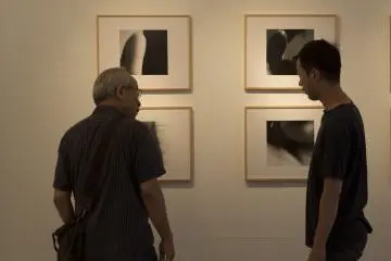 Terada Satoshi discusses his work with a gallery patron