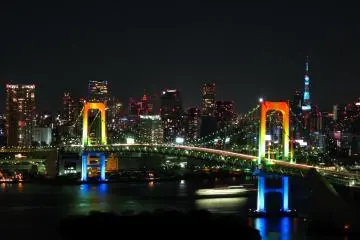 Photo:  Rainbow colored Rainbow Bridge at night – <a href="https://commons.wikimedia.org/wiki/File:Rainbow_colored_Rainbow_Bridge_at_night.jpg" target="_blank" rel="noreferrer noopener nofollow">Gussisaurio</a> / <a href="https://creativecommons.org/licenses/by-sa/3.0/deed.en" target="_blank" rel="noreferrer noopener nofollow">CC BY-SA 3.0</a>