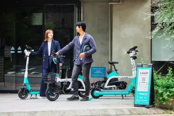 Co-workers chatting next to their LUUP vehicles, holding helmets (Photo: LUUP)